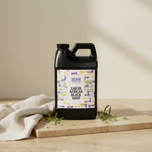Load image into Gallery viewer, Jilyn Skincare Liquid African Black Soap 64oz jug styled with linen and botanicals on warm stone surface