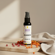 Load image into Gallery viewer, Jilyn Skincare Grandeur Vitamin C Oil 2oz bottle styled with pomegranate seeds and sea buckthorn berries on warm stone surface

